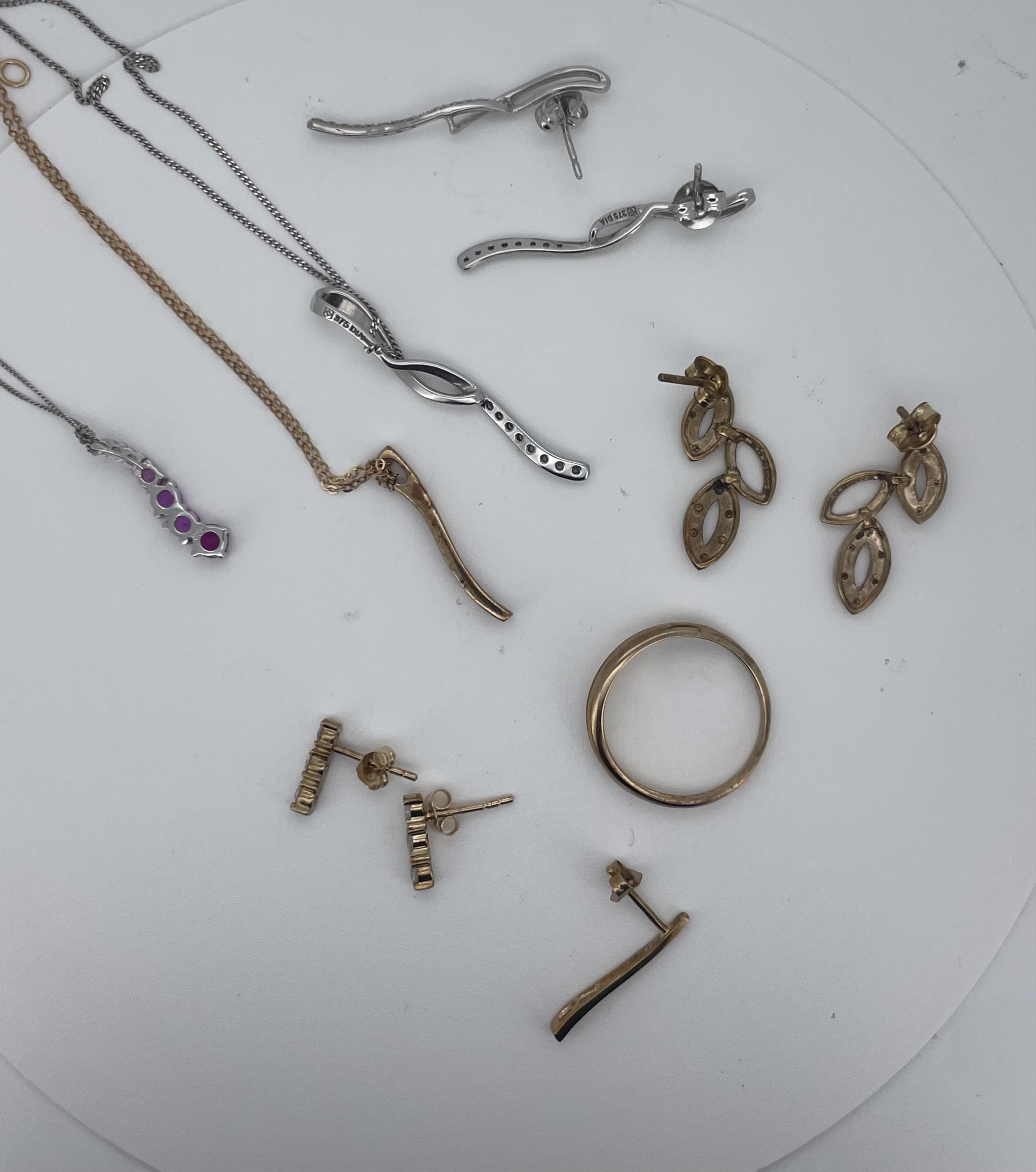 Two modern 375 white metal and gem set line pendants on 375 chains and one similar 375 yellow metal pendant on a 375 chain, four assorted pairs of modern 375 and gem set ear studs including diamond and a modern 9ct gold